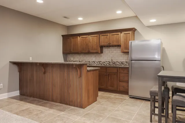 a kitchen with kitchen island granite countertop wooden cabinets and refrigerator