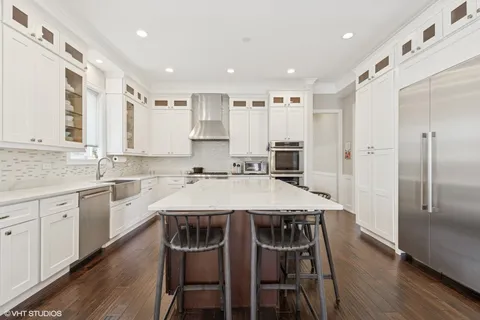 a large kitchen with kitchen island granite countertop a dining table chairs and white cabinets