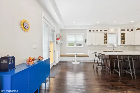 a kitchen with granite countertop a stove a refrigerator a dining table and chairs with wooden floor