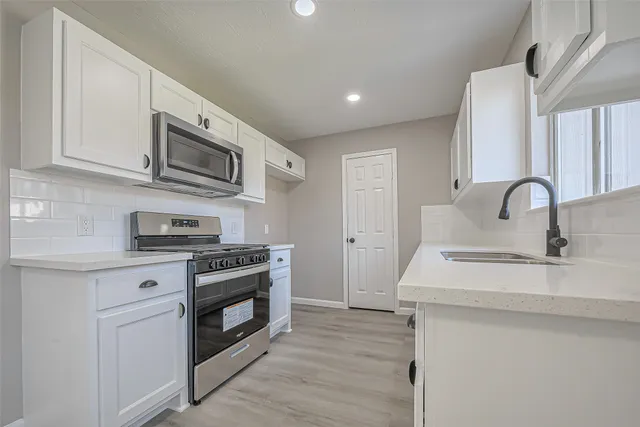 a kitchen with stainless steel appliances granite countertop a stove a sink and a microwave