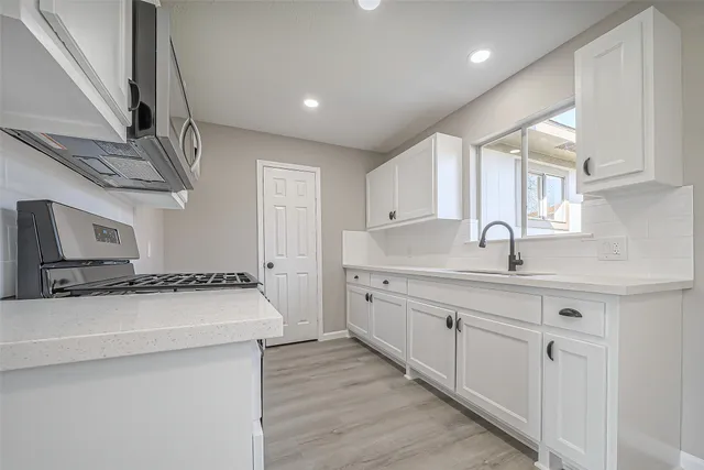 a kitchen with granite countertop a sink stove and cabinets