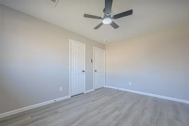 an empty room with wooden floor and ceiling fan