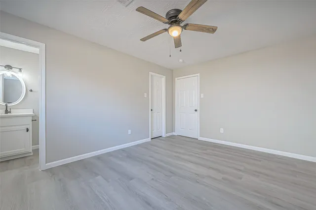 an empty room with a bathroom and a ceiling fan