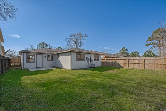 a view of a yard in front of a house with plants and wooden fence