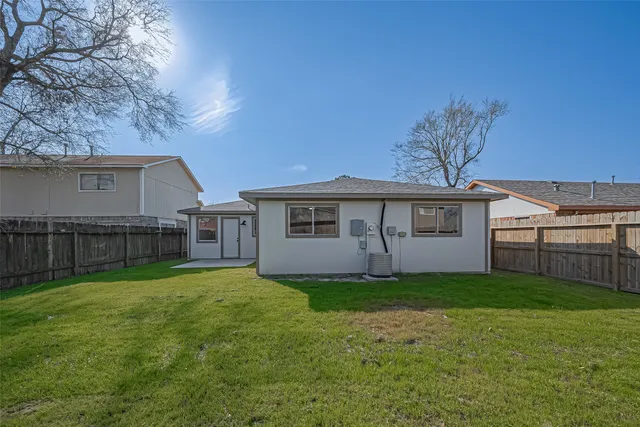 a house that is sitting in the grass with tress in the background