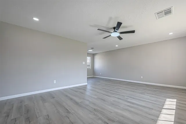 an empty room with wooden floor and ceiling fan