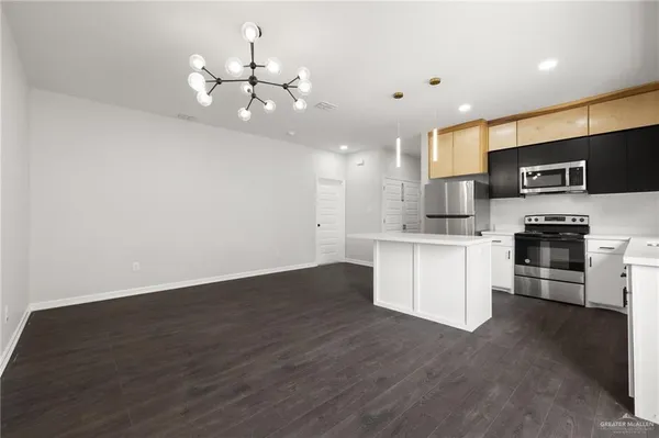 a kitchen with stainless steel appliances granite countertop a stove top oven a sink dishwasher and a refrigerator with wooden floor