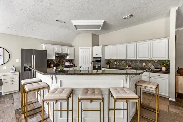 a kitchen with granite countertop a table chairs stove and cabinets