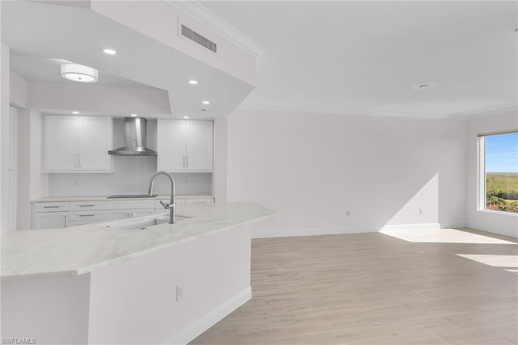 1060 Borghese Lane, Unit 803 Naples, FL 34114 - Photo 16 of 46 Kitchen with crown molding, light wood-type flooring, light stone counters, recessed lighting, and white cabinets