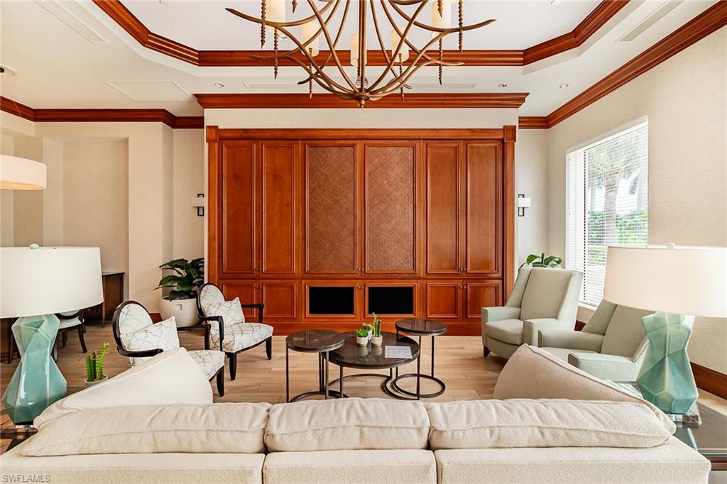 1060 Borghese Lane, Unit 803 Naples, FL 34114 - Photo 36 of 46 Living area featuring a raised ceiling, light wood-style flooring, crown molding, and a chandelier