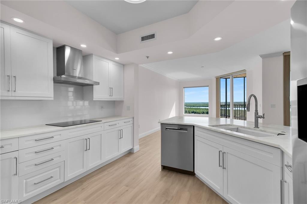 1060 Borghese Lane, Unit 803 Naples, FL 34114 - Photo 5 of 46 Kitchen featuring recessed lighting, white cabinets, wall chimney range hood, light wood-style floors, and ornamental molding