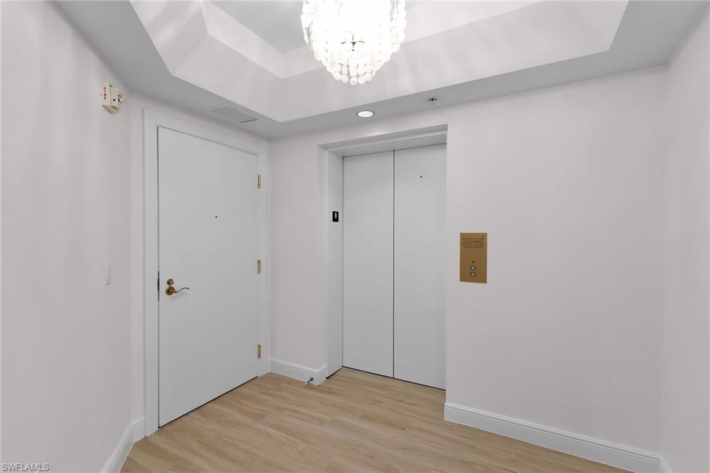 1060 Borghese Lane, Unit 803 Naples, FL 34114 - Photo 8 of 46 Foyer featuring a chandelier, light wood-type flooring, elevator, and a raised ceiling