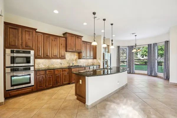 a kitchen with stainless steel appliances granite countertop a refrigerator a oven and a sink
