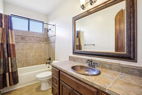 a bathroom with a granite countertop sink toilet a mirror and bathtub
