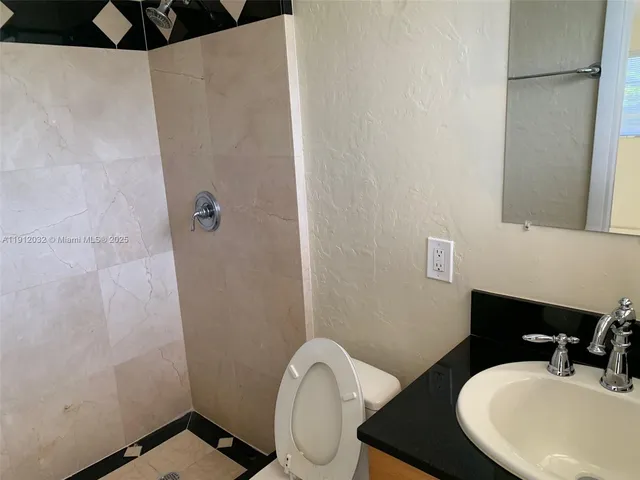 a bathroom with a granite countertop sink toilet and shower