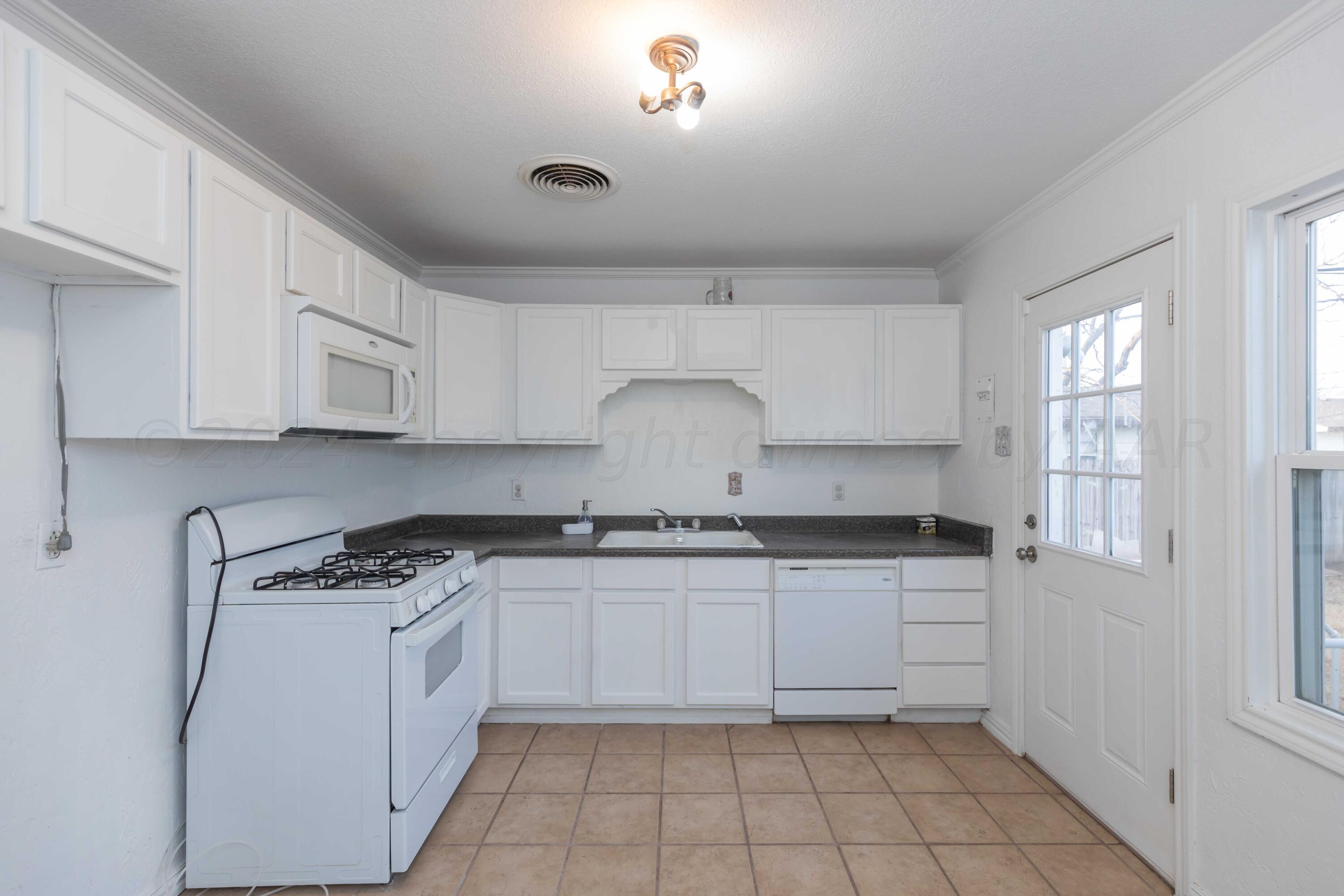 4318 South Monroe Street Amarillo, TX 79110 - Photo 12 of 36 a kitchen with granite countertop white cabinets and white appliances
