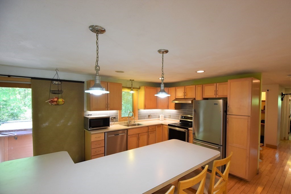 20 Amherst Road Hopkinton, MA 01748 - Photo 4 of 27 a kitchen with stainless steel appliances a refrigerator a sink a stove a dining table and chairs