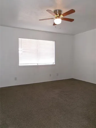 an empty room with a window and a ceiling fan