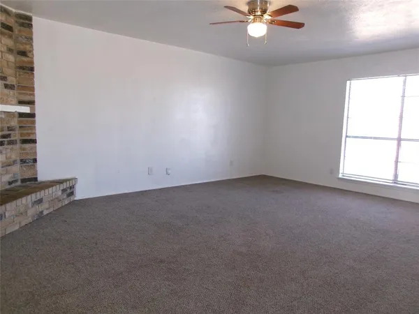 an empty room with a window and a fan