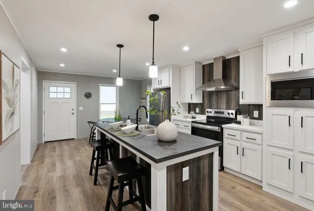 a kitchen with stainless steel appliances granite countertop a sink a stove and a wooden floors