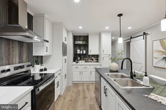 a kitchen with stainless steel appliances kitchen island granite countertop a refrigerator a sink dishwasher a stove and white cabinets with wooden floor