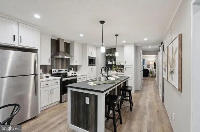 a kitchen with stainless steel appliances kitchen island a white table chairs and a refrigerator