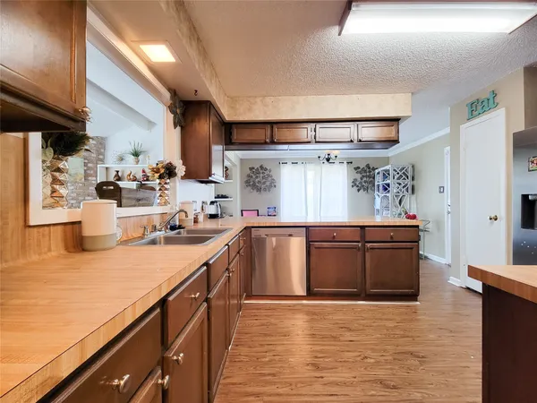 a kitchen with stainless steel appliances granite countertop a sink dishwasher stove and wooden cabinets