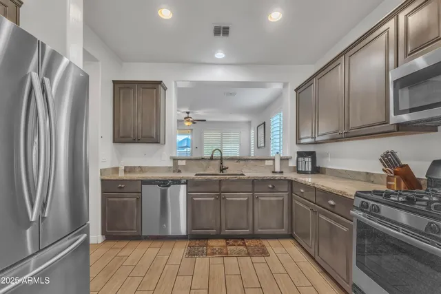 a kitchen with stainless steel appliances granite countertop a stove top oven a sink dishwasher a refrigerator and cabinets with wooden floor