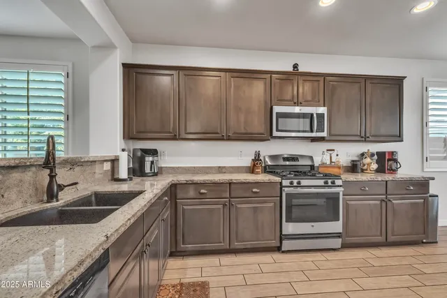 a kitchen with stainless steel appliances granite countertop a sink stove and cabinets