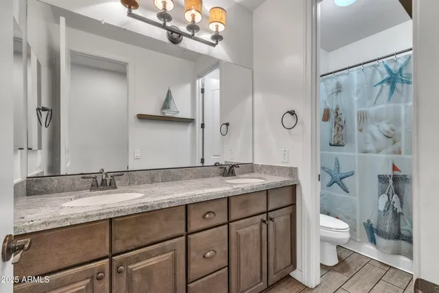 a bathroom with a granite countertop sink a toilet a mirror and shower