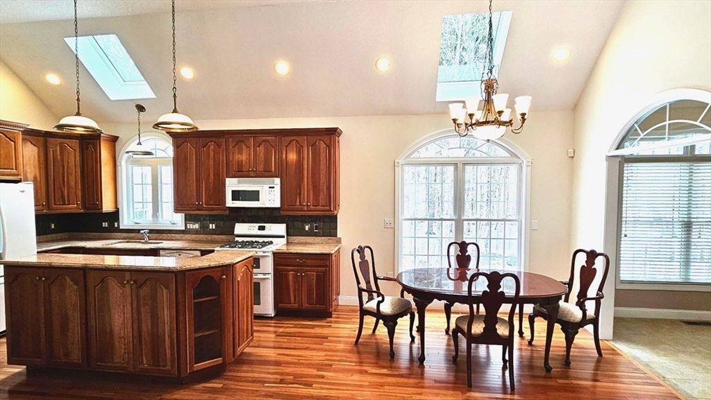 16 Arbor Road, Unit 16 Dracut, MA 01826 - Photo 2 of 13 a kitchen with stainless steel appliances granite countertop a stove a sink dishwasher a dining table and chairs with wooden floor