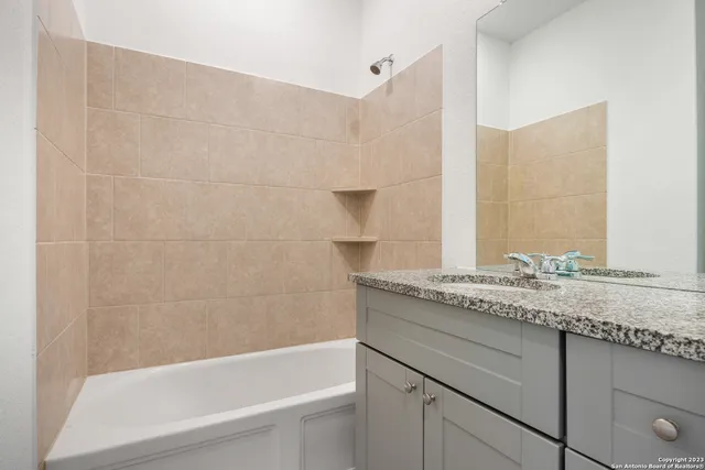 a bathroom with a granite countertop bathtub sink vanity and toilet