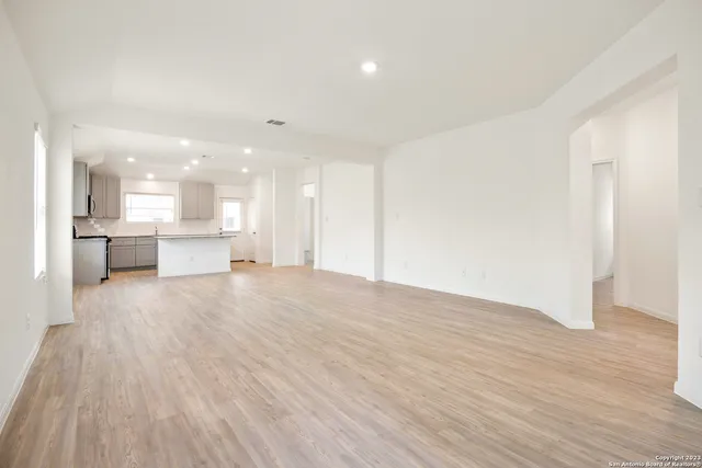 a view of kitchen and empty room with wooden floor