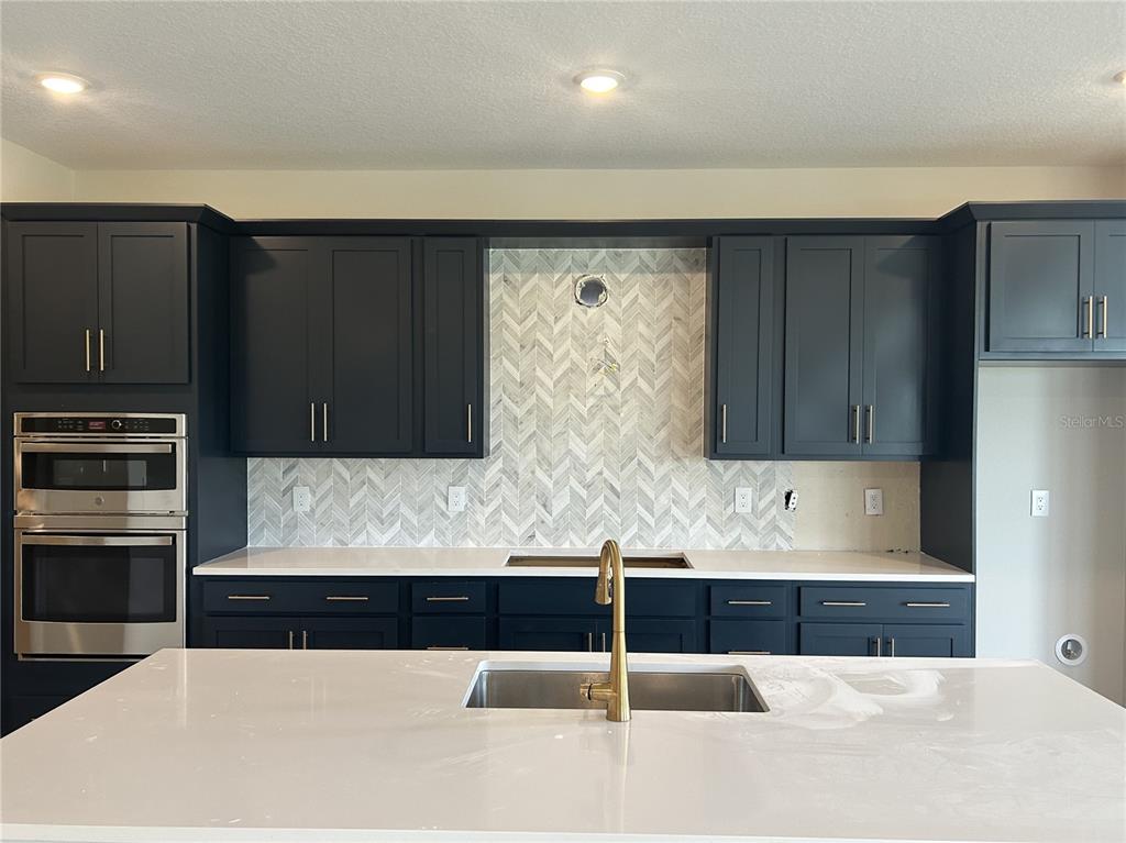 10026 Hidden Hammock Loop Parrish, FL 34221 - Photo 13 of 34 a kitchen with kitchen island granite countertop wooden cabinets and stainless steel appliances