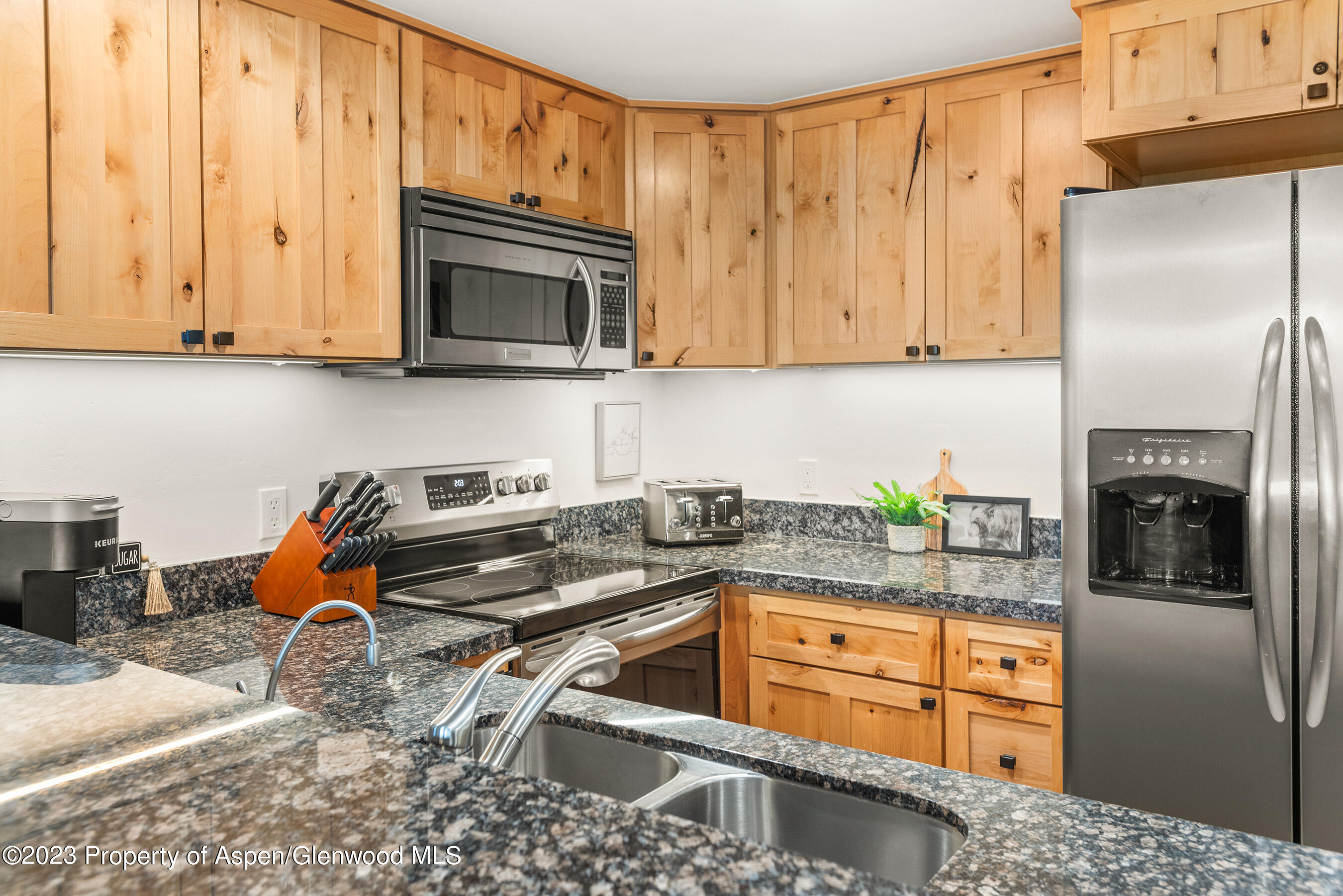 55 Upper Woodbridge Road, Unit G3 Snowmass Village, CO 81615 - Photo 10 of 44 a kitchen with stainless steel appliances granite countertop a refrigerator a stove and a sink with wooden cabinets