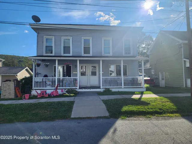 front view of a brick house with a yard