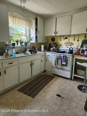 a kitchen with a sink a stove cabinets and a window