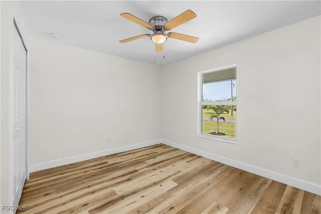 an empty room with window and ceiling fan