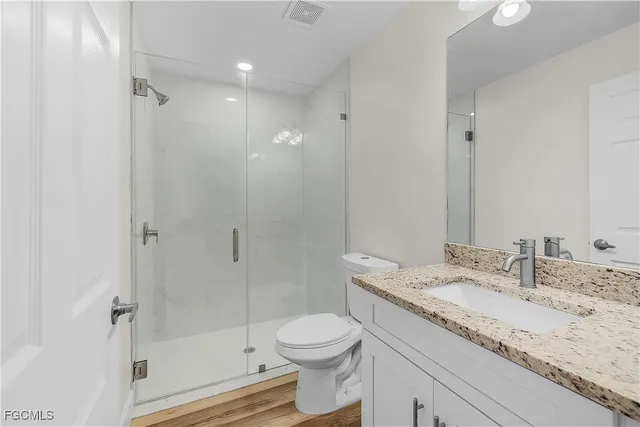 a bathroom with a granite countertop sink a toilet and shower