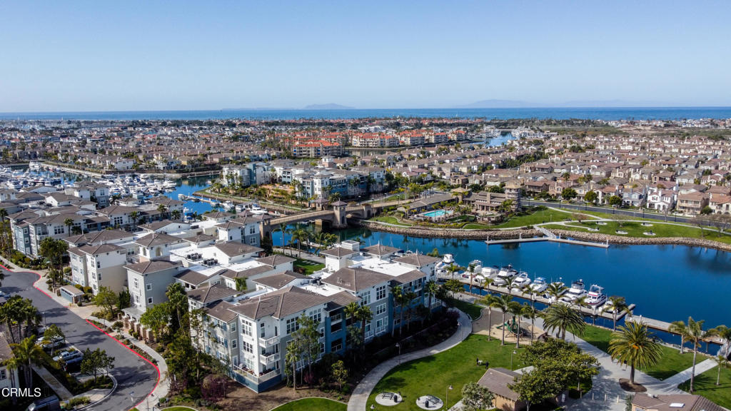 an aerial view of a city with lots of residential buildings ocean and mountain view in back
