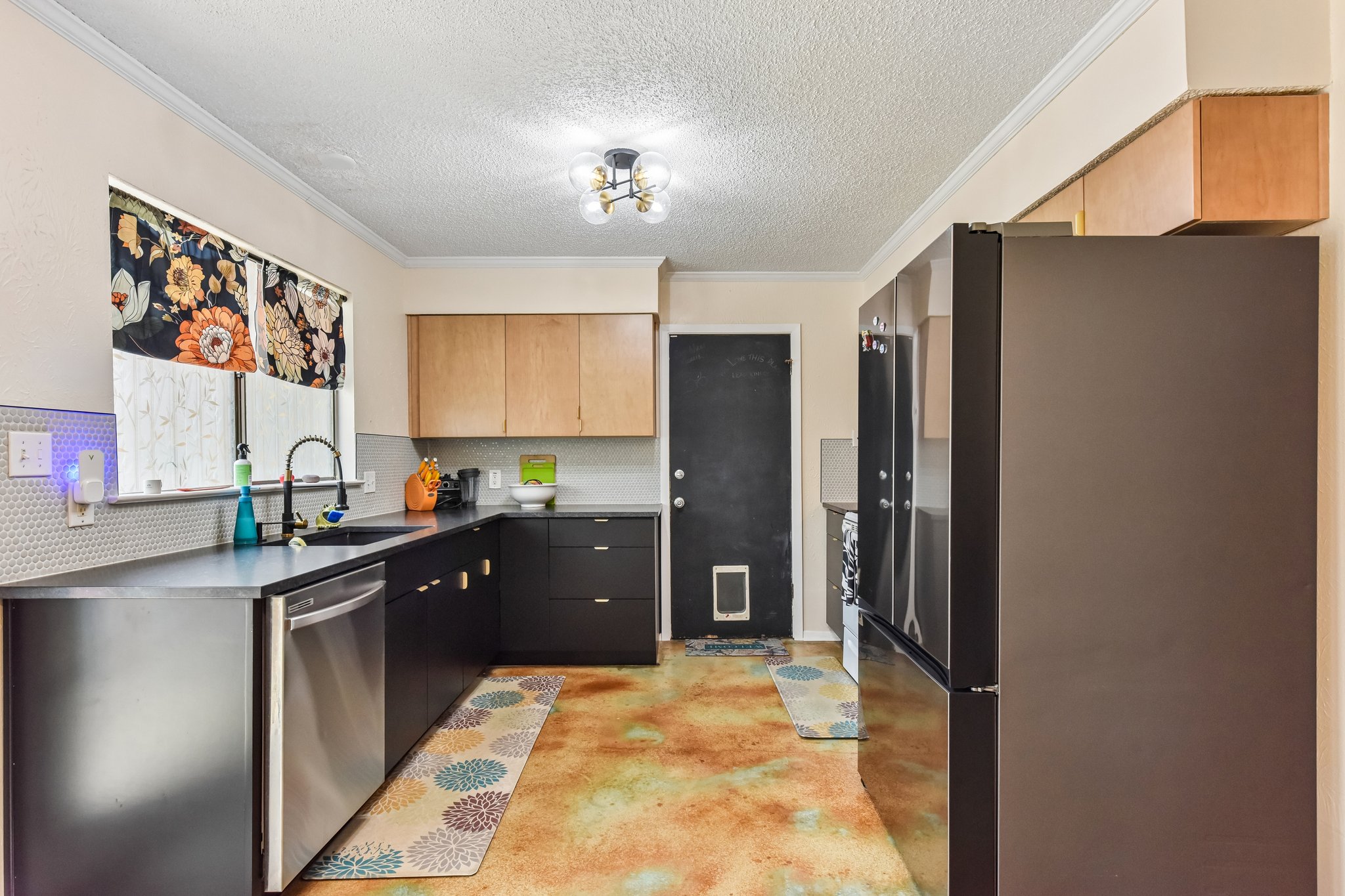 9610 Covey Ridge Lane Austin, TX 78758 - Photo 1 of 22 Kitchen featuring stainless steel appliances, black and light wood cabinetry, dark countertops, and a white hexagonal tile backsplash