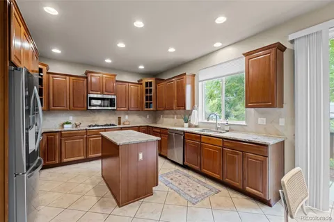 a kitchen with kitchen island granite countertop wooden cabinets stainless steel appliances a sink and a window