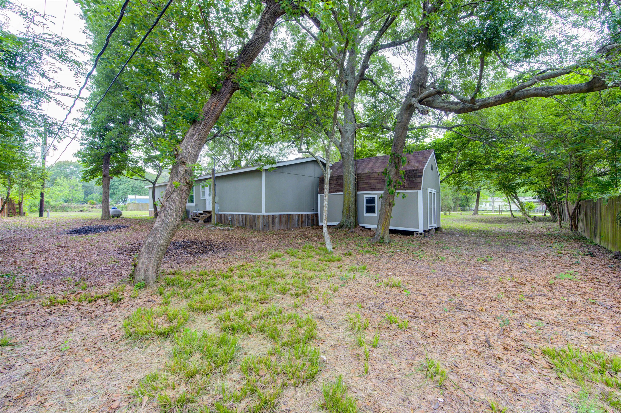 30226 Davis Street Magnolia, TX 77355 - Photo 41 of 50 This photo shows a cozy home nestled among mature trees, offering a spacious, shaded yard with a peaceful, natural setting. Perfect for privacy and outdoor enjoyment.