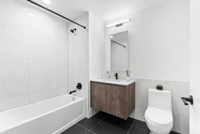 a bathroom with a toilet a sink a mirror a bathtub and vanity