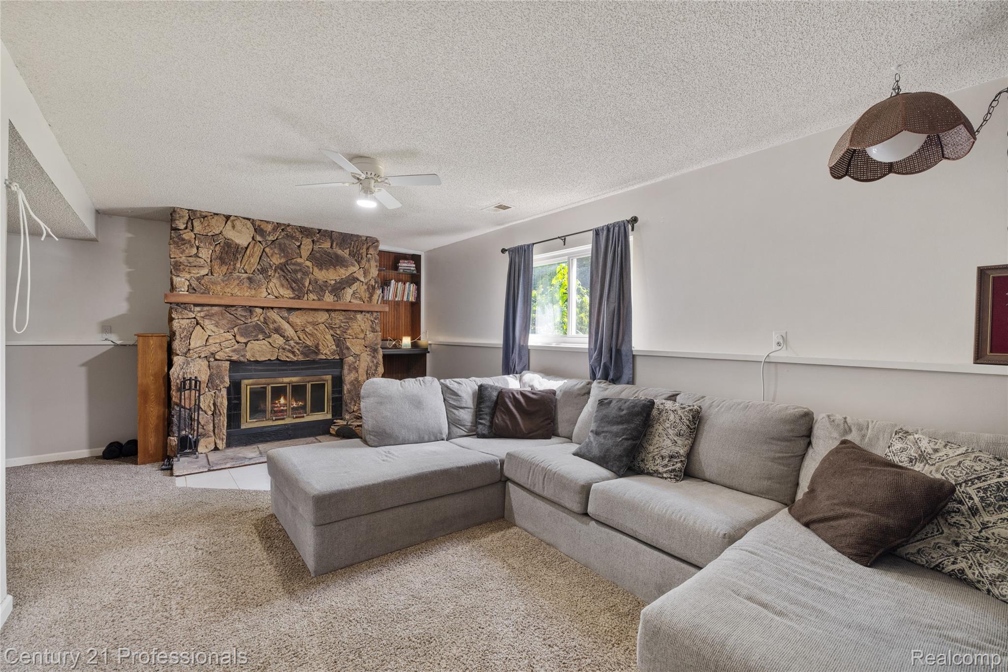 15037 Hogan Road Linden, MI 48451 - Photo 13 of 38 Cozy living space featuring a prominent stone fireplace with a wood mantle