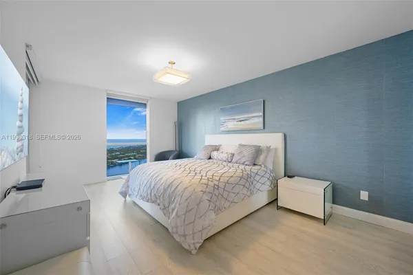 a bedroom with a bed and a flat tv screen on dresser