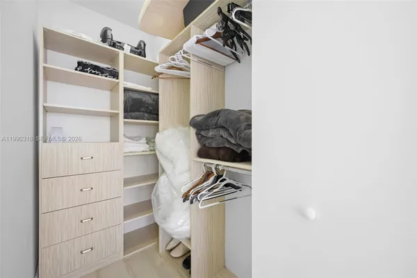 a walk in closet with wooden floor