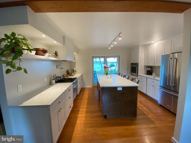 a kitchen with stainless steel appliances kitchen island granite countertop a refrigerator a stove and a sink