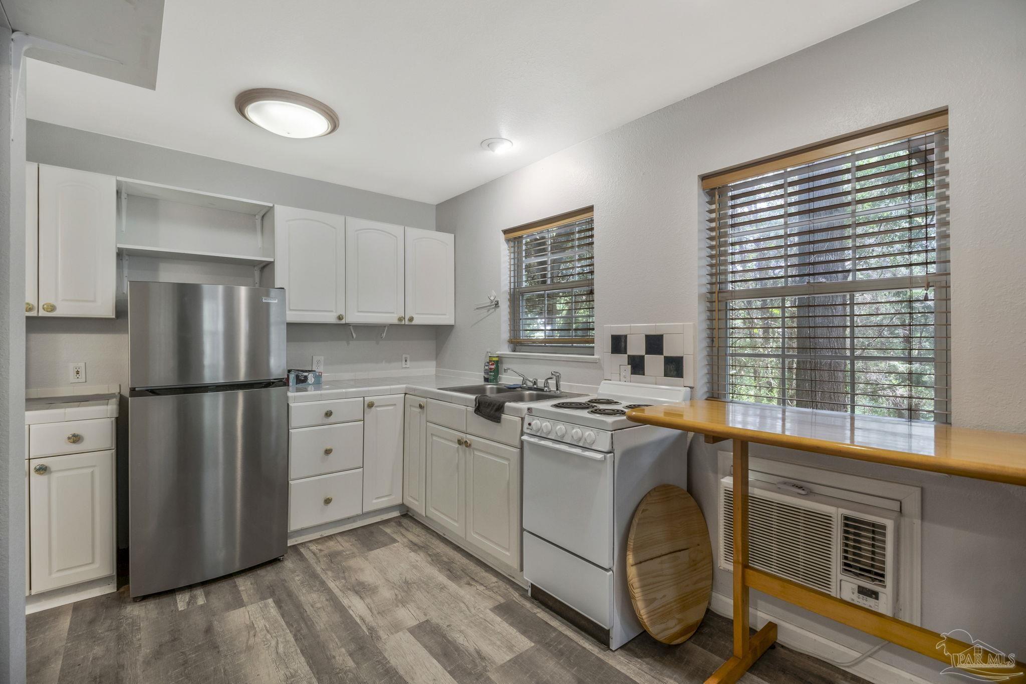 10290 West Lake Road Milton, FL 32583 - Photo 2 of 53 a kitchen with stainless steel appliances granite countertop a refrigerator a sink dishwasher a stove and white countertops with wooden floor