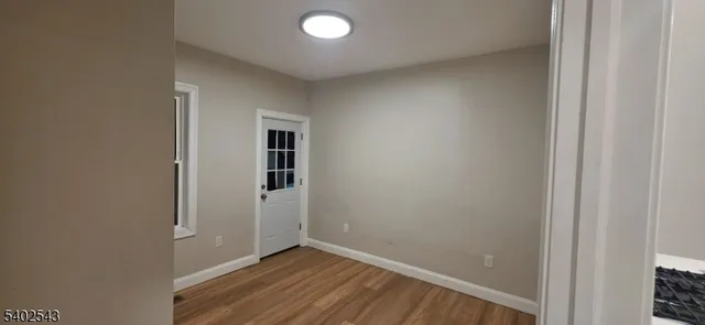 a view of an empty room with wooden floor and closet